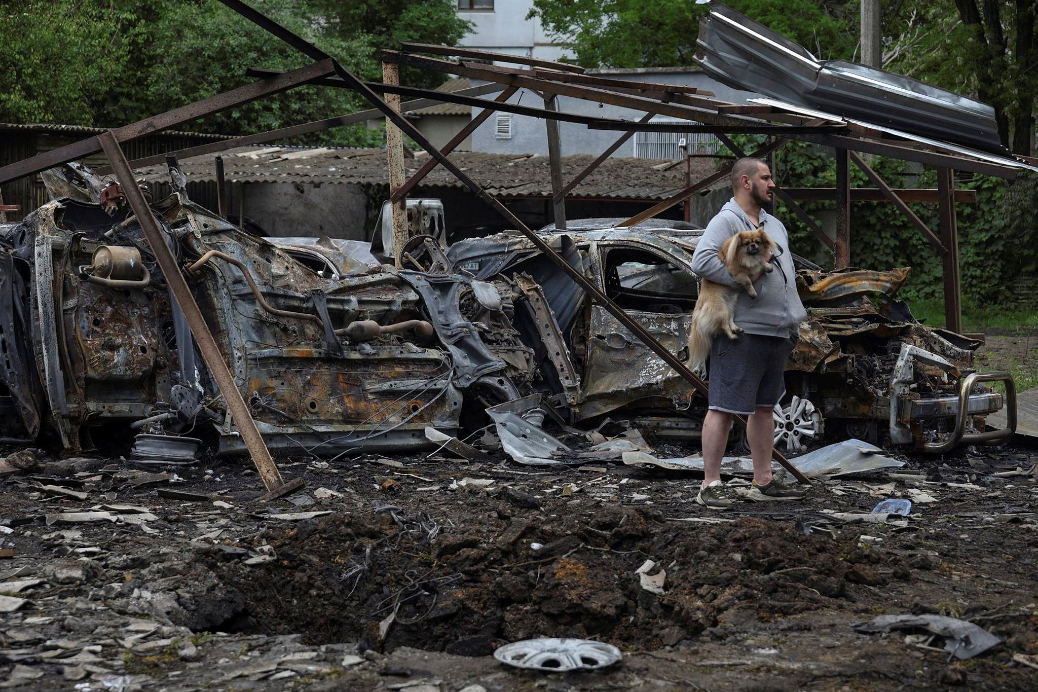 A resident with a dog stands next to cars destroyed in a residential area during a Russian drone strike, amid Russia's attack on Ukraine, in Odesa, Ukraine, May 25 (Photo: Reuters)