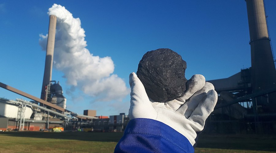 Worker holding up a piece of coal in front of a coal firing power plant in the Netherlands.