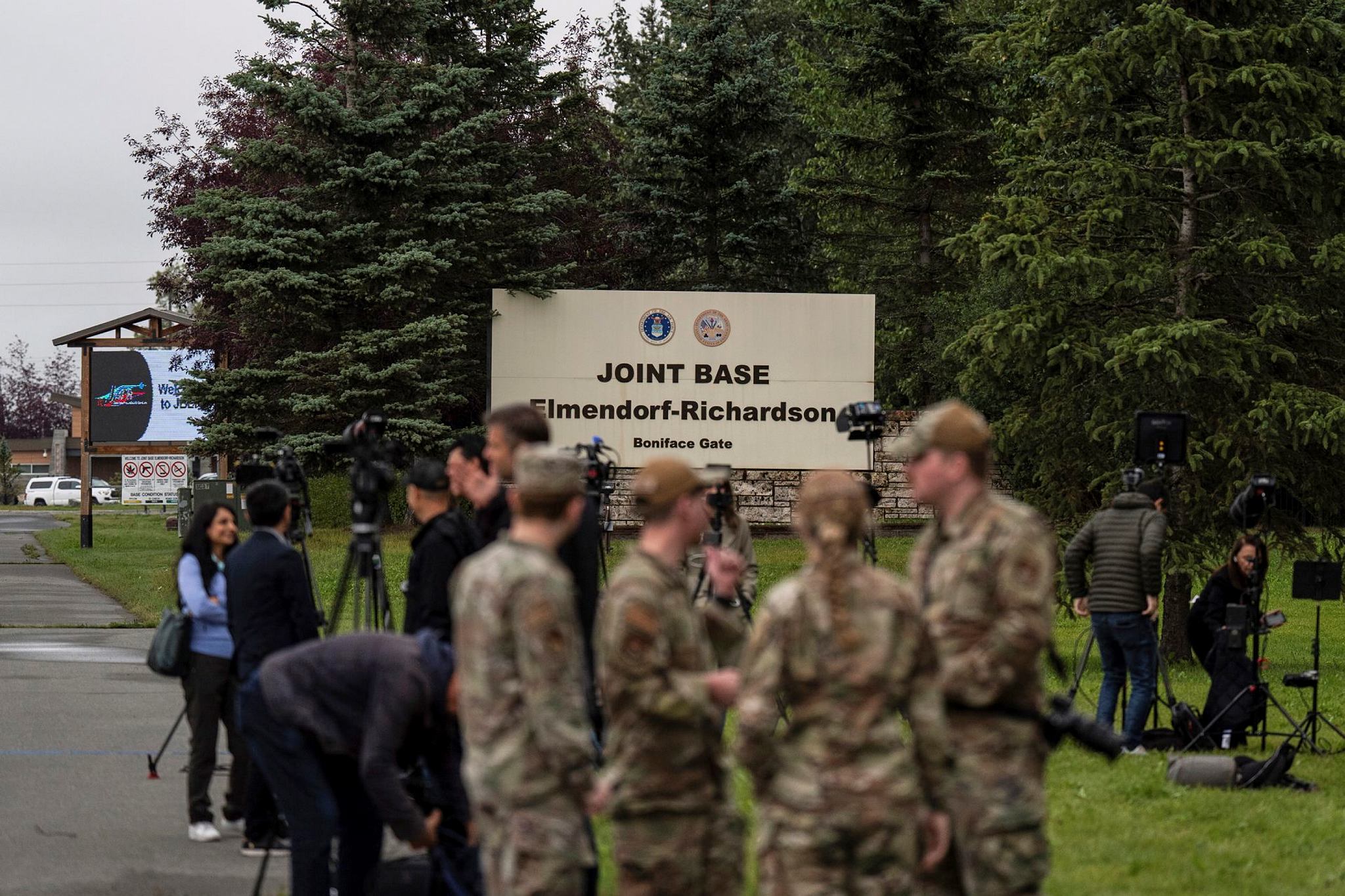 Military personnel and the media stand outside Joint Base Elmendorf-Richardson in Alaska ahead of a meeting between Donald Trump and Vladimir Putin. (AP Photo)